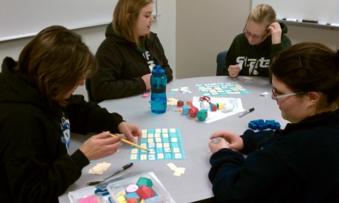 Four students playing Geometry Vocabulary Block on two game boards.